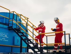 Veolia engineers in red safety gear inspecting an industrial water treatment facility with a blue processing unit.