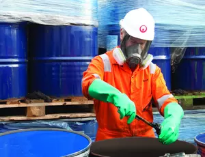 Veolia Korea worker handling hazardous waste drums in protective gear, showcasing safe and compliant toxic waste management.