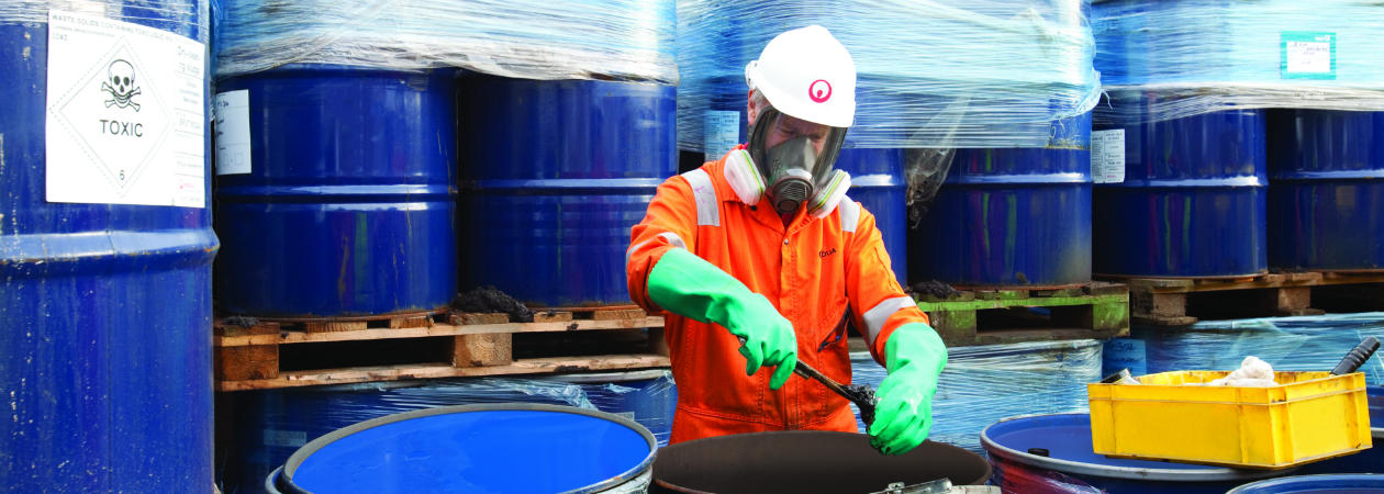 Veolia Korea worker handling hazardous waste drums in protective gear, showcasing safe and compliant toxic waste management.